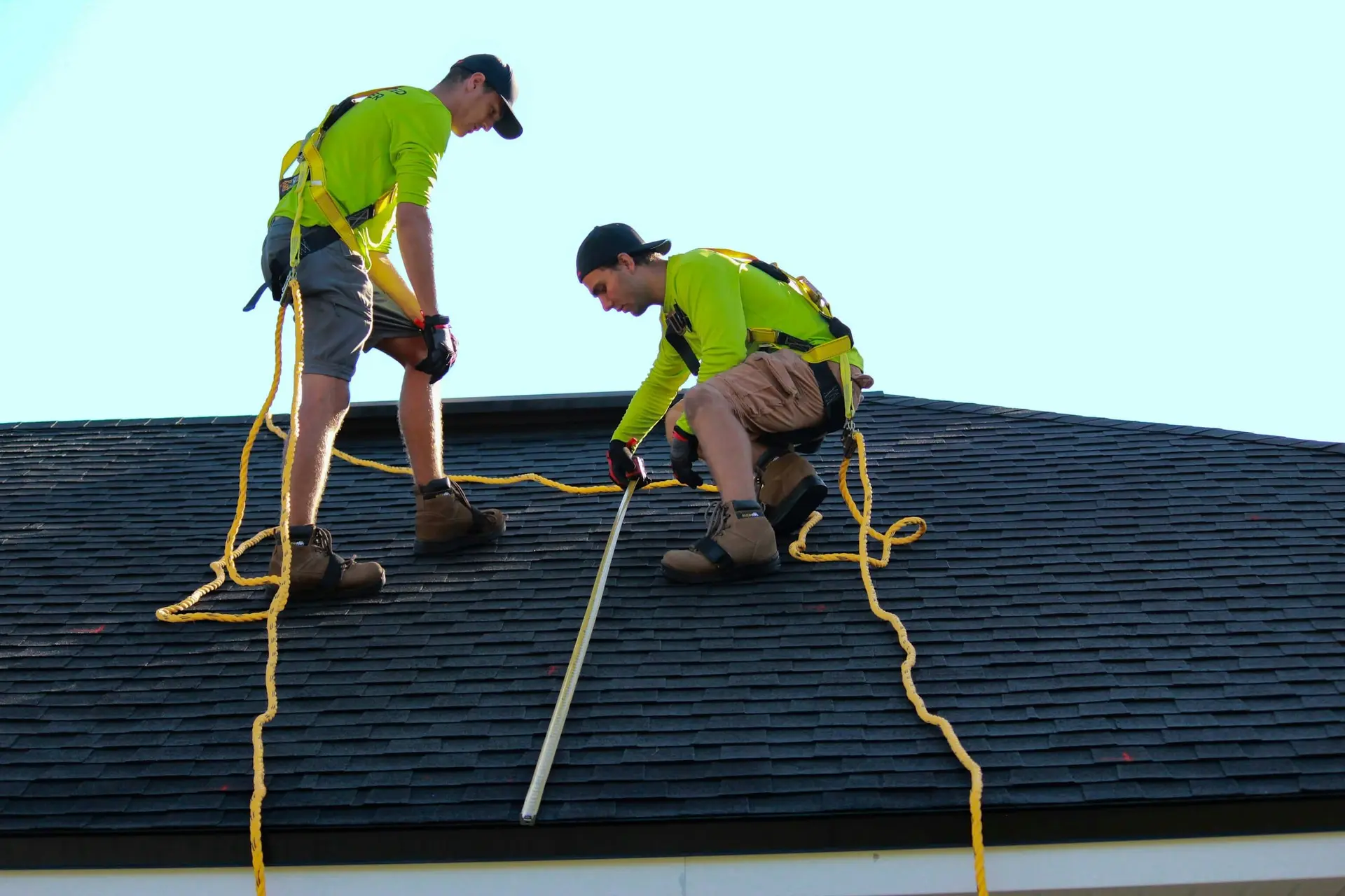 Roofers measuring a roof during a detailed inspection