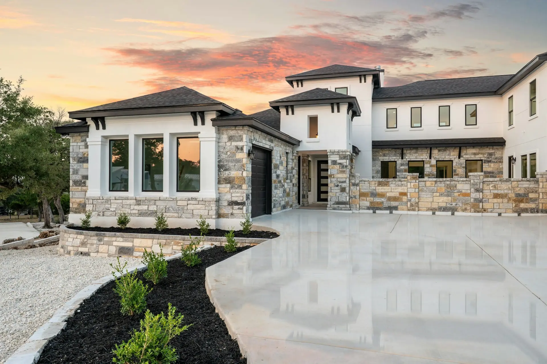 Stone and stucco residence with a hip roof and concrete drive